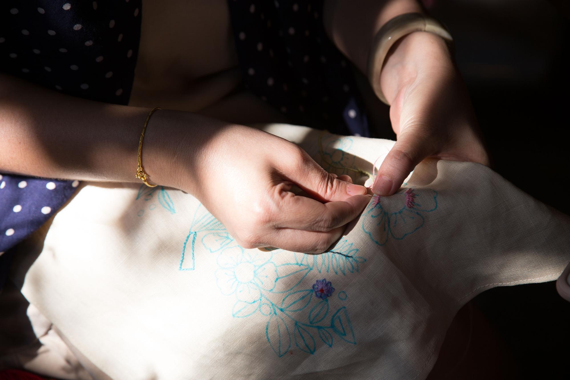 Artist stitching a simple motif on fabric